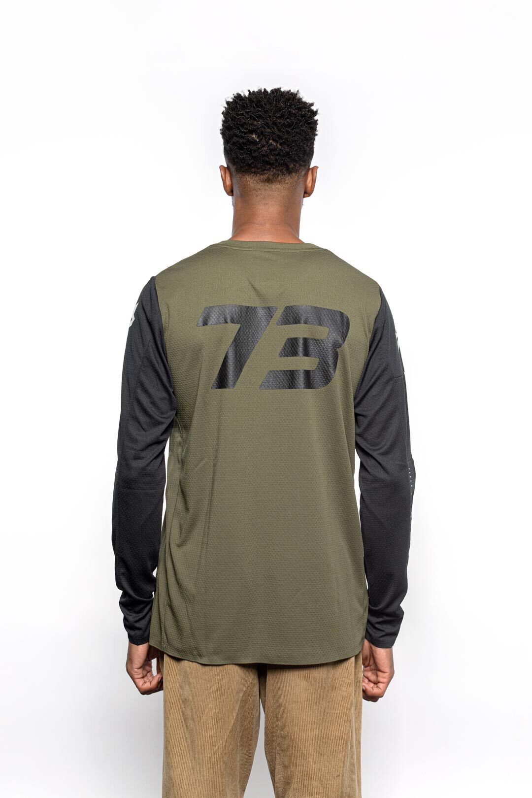 Male model back view of black and olive Premium long sleeve athletic moto hoon jersey.