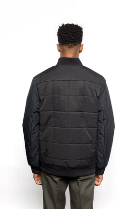 Back view of Male model wearing Sipes Varsity Jacket in black colorway.