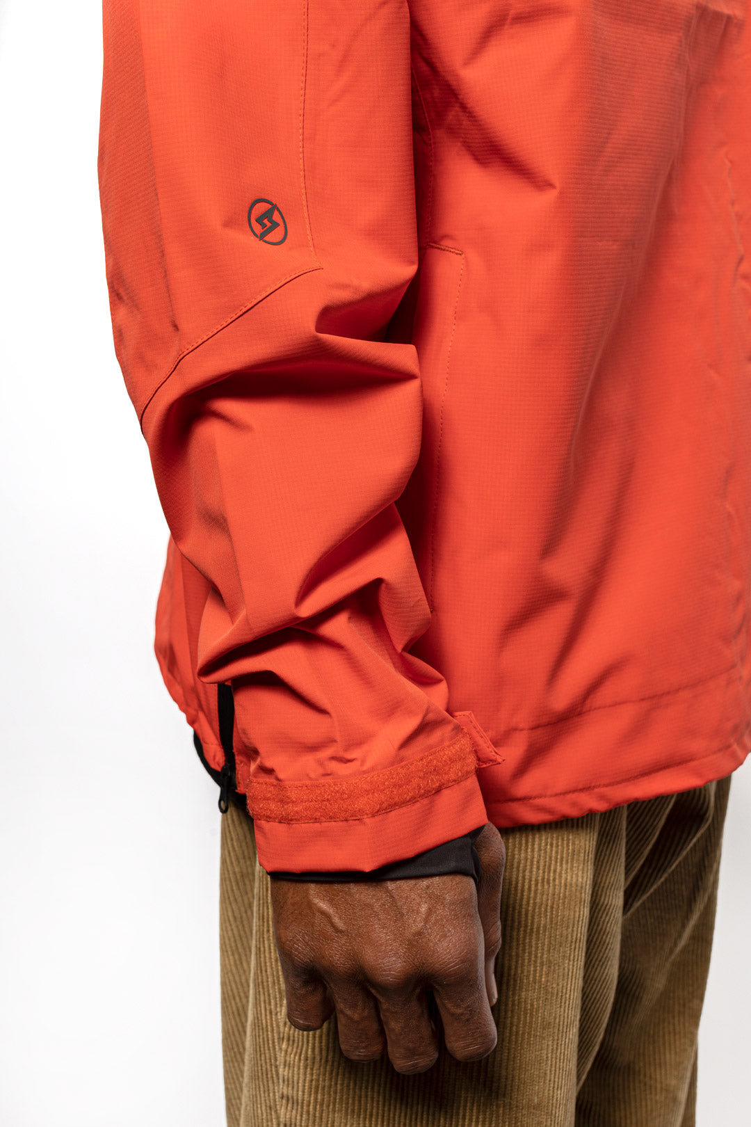 Side sleeve detail shot of male model wearing Vale Packable Anorak in blood orange colorway.